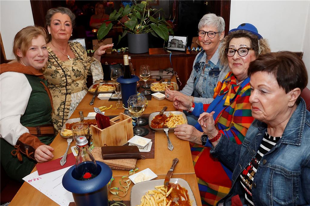 Mehrere Frauen sitzen an einem Tisch und essen Pommes.