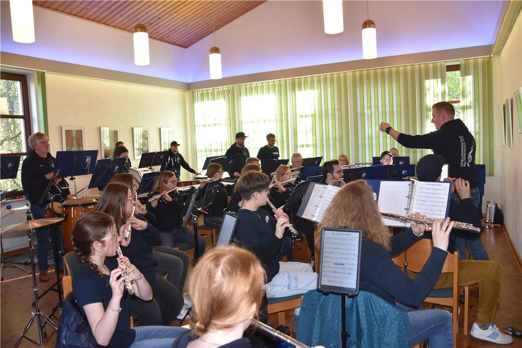 Spielmannszug Bausenhagen fährt zur Deutschen Meisterschaft Die Mitglieder des Spielmannszugs Fröndenberg-Bausenhagen sitzen in einem Probenraum vor Dirigent Hendrik Schwarzkopf.