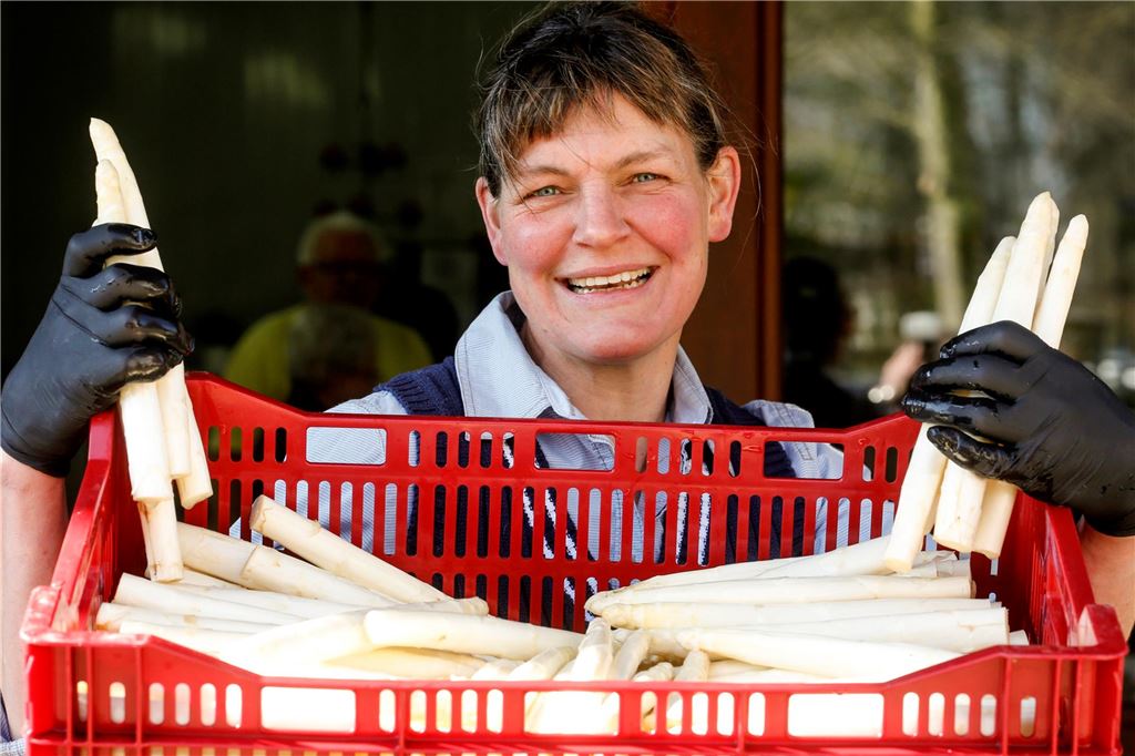 Spargelernte auf dem Hof Schulze Elberg in vollem Gange Antje Schulze Elberg vom Hof Schulze Elberg in Bergkamen-Rünthe hält mehrere Stangen weißen Spargels in den Händen. Sie lächelt in die Kamera.