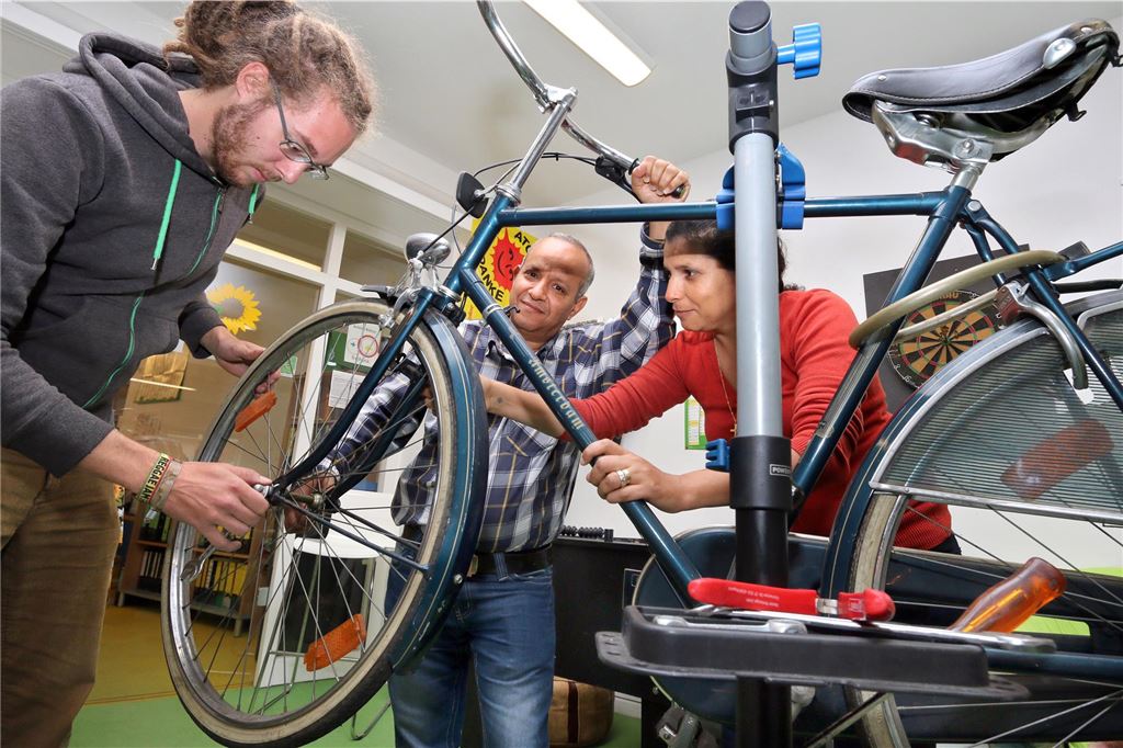 Unna lässt die Fahrradstreifen allmählich verblassen Carsten Hellmann repariert mit zwei Helfern ein Fahrrad, das in einen Montageständer eingespannt ist.