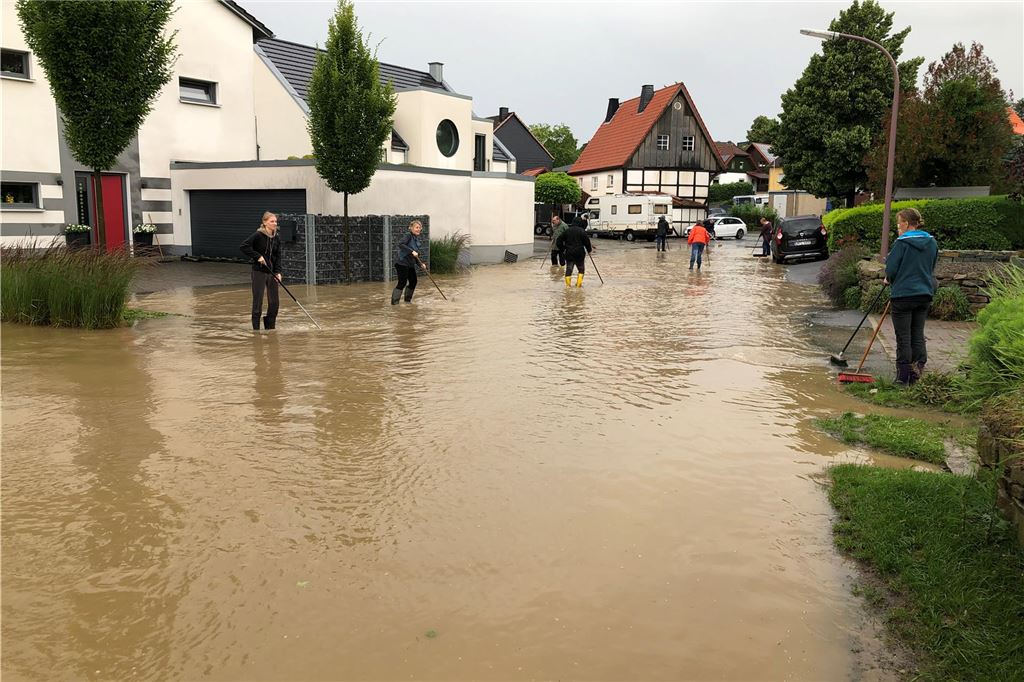 Anhaltende Hochwassersorgen: Dorfstraße in Billmerich erneut unter Wasser Anwohner der Billmericher Dorfstraße in Unna versuchen das Wasser bei dem Starkregenereignis im Juli 2021 mit Besen von ihrem Grundstück fernzuhalten.
