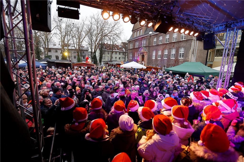 Viele Kinder mit Zipfelmützen stehen auf der Bühne des Holzwickeder Weihnachtsmarktes.