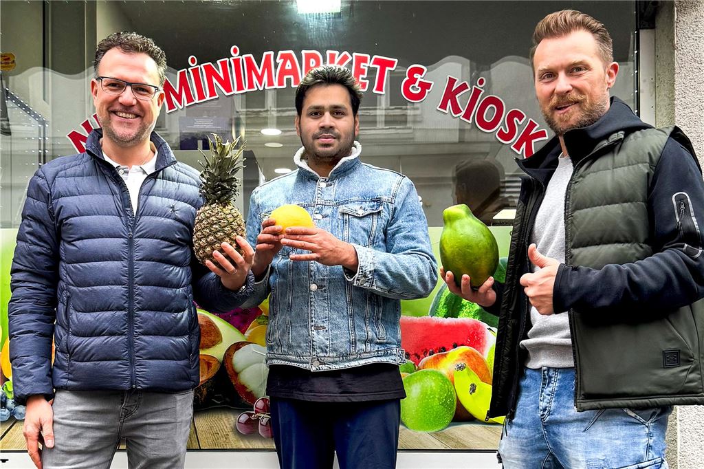 Minimarkt hat neuen Betreiber: Brot und Gemüse bis tief in die Nacht Drei Männer stehen mit exotischem Obst vor einem Minimarkt in Schwerte.