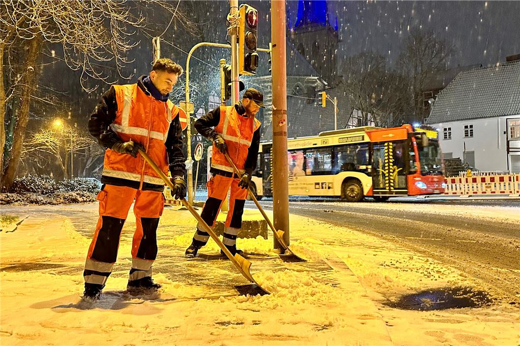 Unfälle durch Schnee und Glätte am Abend im Kreis Unna Zwei Männer räumen einen verschneiten Gehweg.