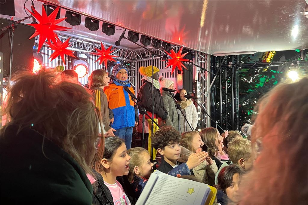 Weihnachtsmarkt 2024: Das Programm am letzten Wochenende Weihnachtsmarkt 2024 in Unna. Menschen stehen vor der Bühne an der Sparkasse. Auf der Bühne steht Unnaer Bürgermeister Dirk Wigant und hält ein Mikrofon in der Hand.