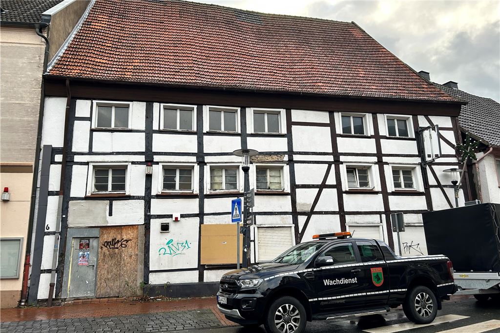 Die Silvesternacht 2023: Feuerwehr muss zu acht Einsätzen ausrücken Ein altes Fachwerkhaus, was recht heruntergekommen ist. Davor steht ein schwarzer Wagen auf dem "Wachdienst" steht. Es wurde gerade ein neues Brett vor einem Fenster angebracht.