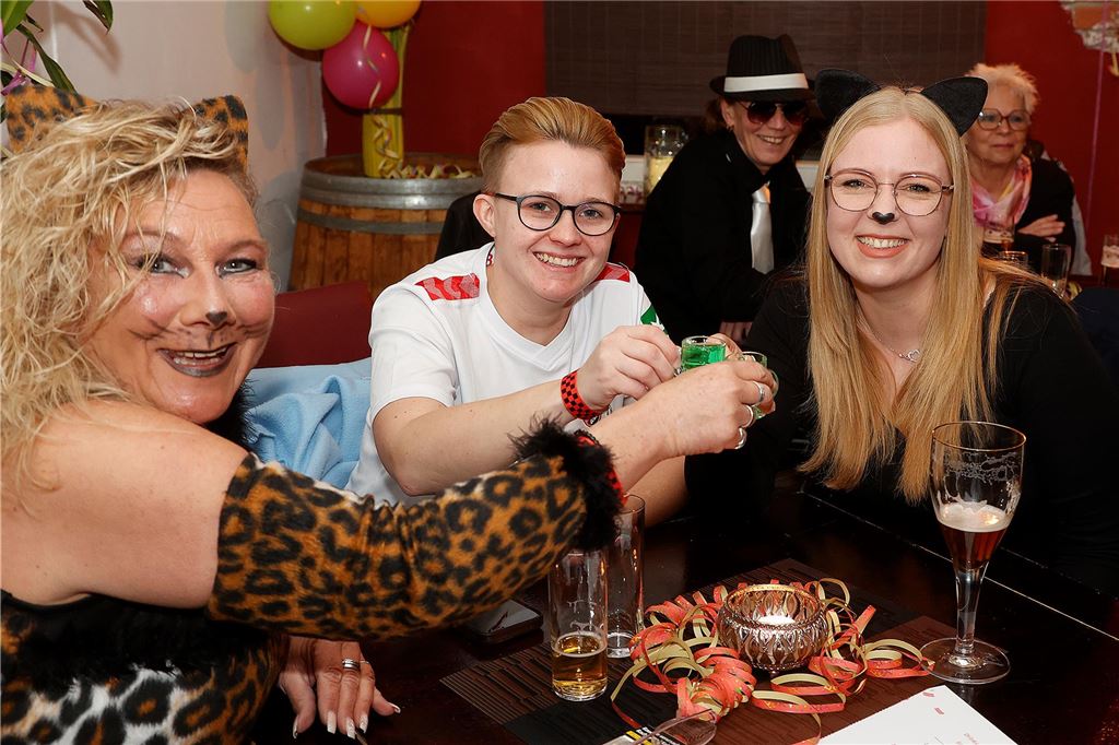 Zwei als Katzen verkleidete Frauen mit grünen Shots in den Händen.