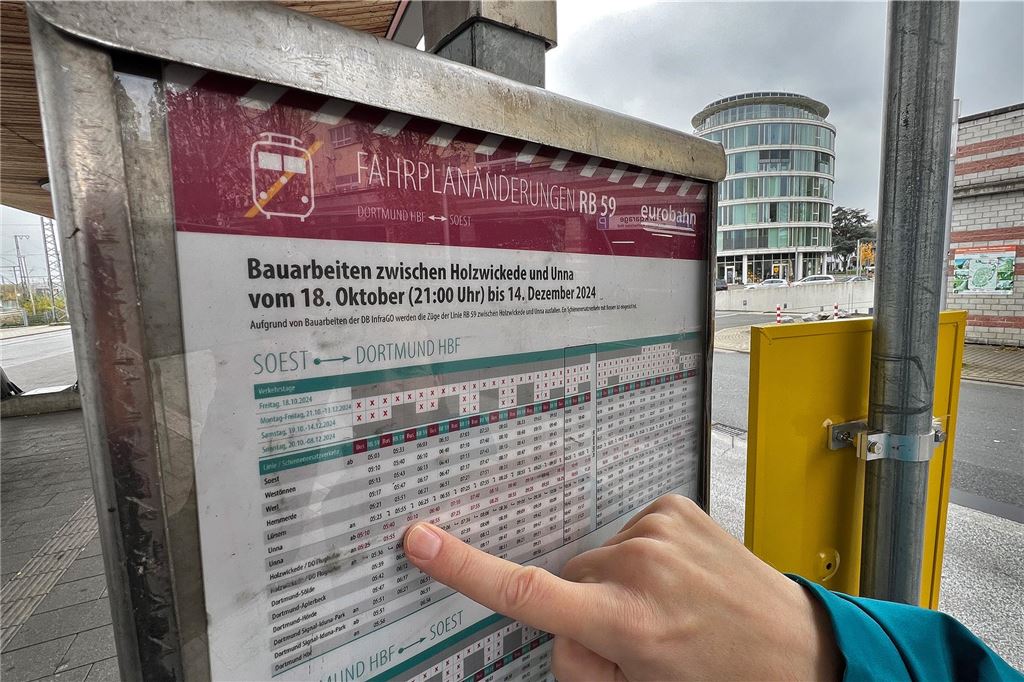 Pendler verärgert: Bahn-Ersatzbusse fahren nicht Ein Mann zeigt mit dem Finger auf einen Busfahrplan.