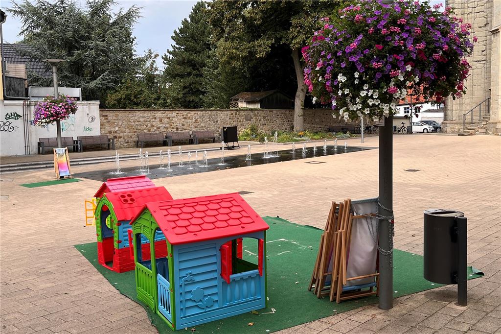 Kirche klärt rätselhafte „Chemie“-Hinweise auf: Chlor im Wasserspiel Auf dem Kirchplatz in Unna stehen Spielhütten für Kinder. Dahinter plätschert Wasser aus einem Boden-Wasserspiel.