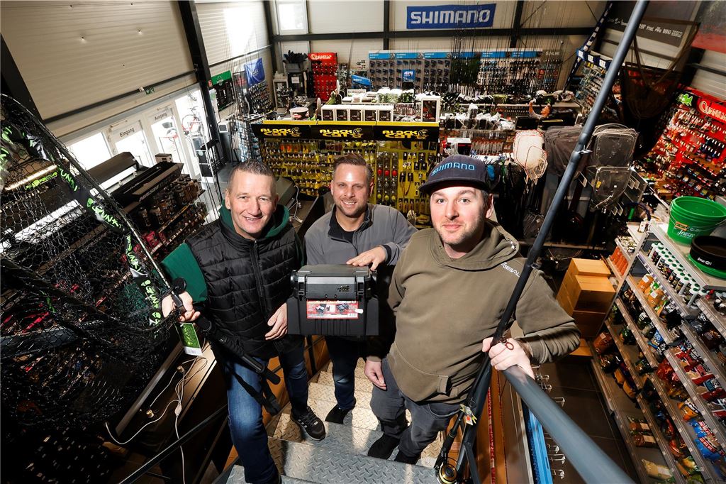 Damit der Karpfen in Stimmung kommt Auf der Treppe zum Lager stehen (v.l.) Jürgen Willig, Kai Malzahn und Tobias Peske. Im Erdgeschoss halten sie 12.000 unterschiedliche Produkte fürs Profiangeln vor.