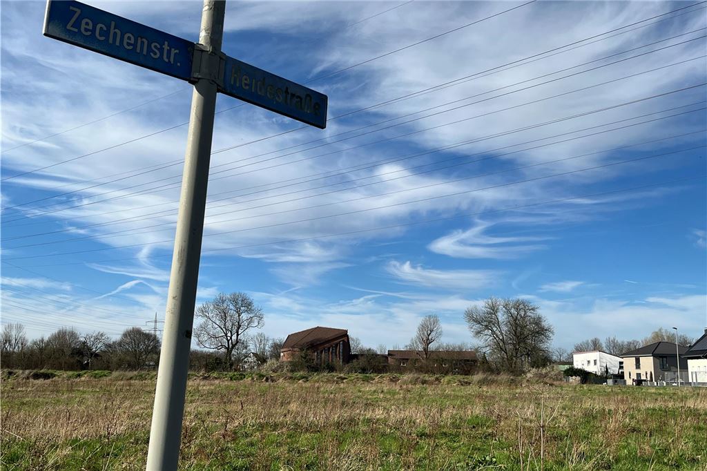 Baustart in Kürze: In Königsborn entstehen 300 neue Großgaragen Ein Wegschild in Unna-Königsborn weist nach links die Zechenstraße und nach rechts die Heidestraße aus. Im Hintergrund ist eine Wiese und die Kirche der Evangelisch-Freikirchlichen Gemeinde in Unna zu sehen.