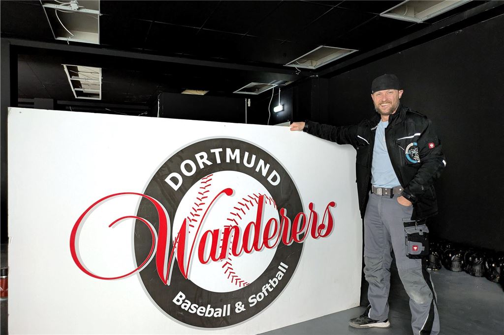 Schwertes neue Event-Location: „The Stage“ wird mit Party eröffnet Sascha Schubert steht in der Eventlocation "The Stage" in Schwerte neben dem Logo des Baseball-Vereins Dortmund Wanderers.