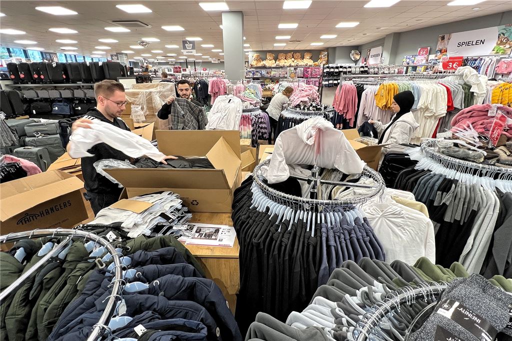 Akkordarbeit am Warenregal: Erster Blick in den neuen Woolworth-Markt Aufbügeln – so nennt sich bei Woolworth das Aufhängen der zuvor in Kartons angelieferten Textilien auf Kleiderbügeln.