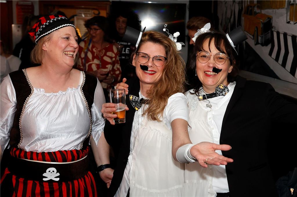 Drei Frauen, von denen zwei ein Kostüm tragen. Sieht aus wie ein Charlie Chaplin bestehend aus zwei Frauen.