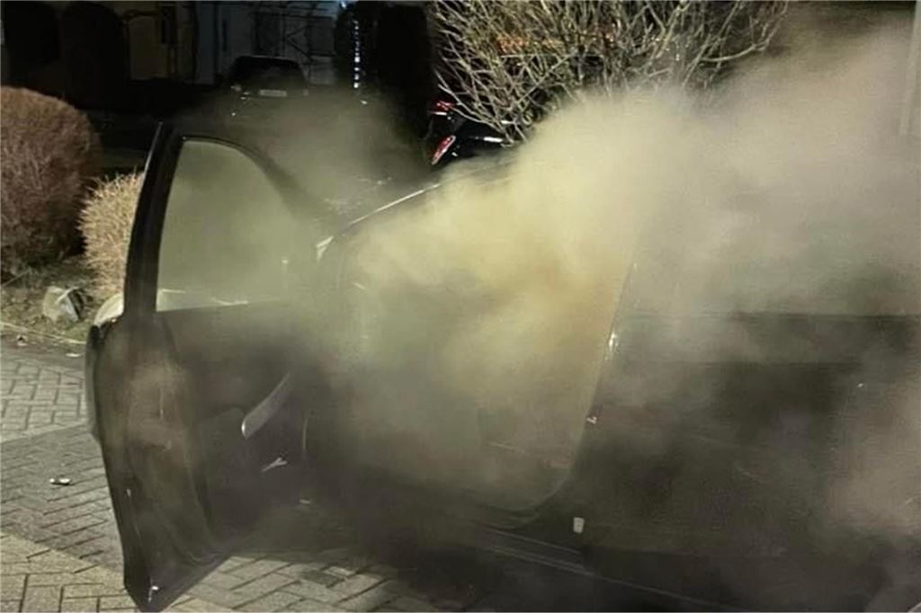 Ruhige Silvesternacht 2023 für die Freiwillige Feuerwehr Bergkamen Ein schwarzes Auto mit offener Tür, das von innen mächtig qualmt. Man sieht fast gar nicht, außer den Konturen des Wagens.