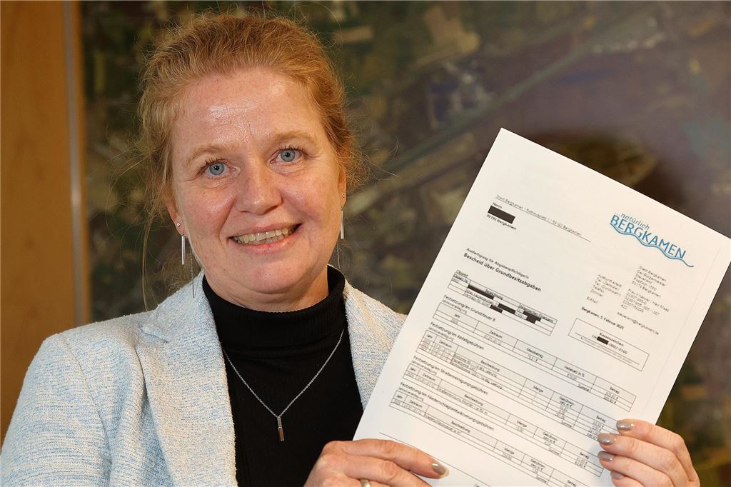 Bergkamen wird den Grundsteuerhebesatz anpassen müssen Kämmerin Sandra Diebel lächelt in die Kamera und hält einen Abgabebescheid in den Händen.