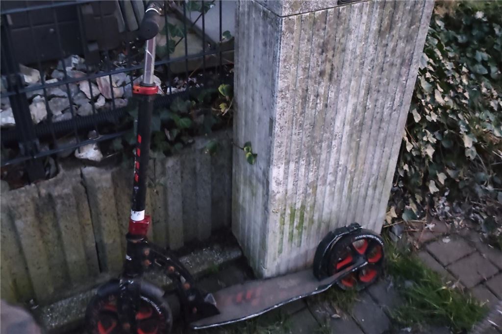 Ein E-Scooter steht an einem Stromkasten. 
