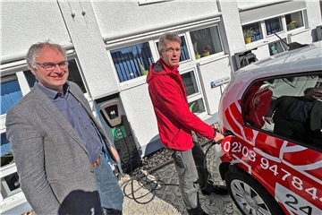 Caritas-Vorstand Ralf Plogmann (l.) und Mitarbeiter Bernd Bernkendorf an einer der Ladestationen für die E-Autos: Der Caritasverband versorgt sich an seiner Zentrale in Unna nun weitgehend autark.