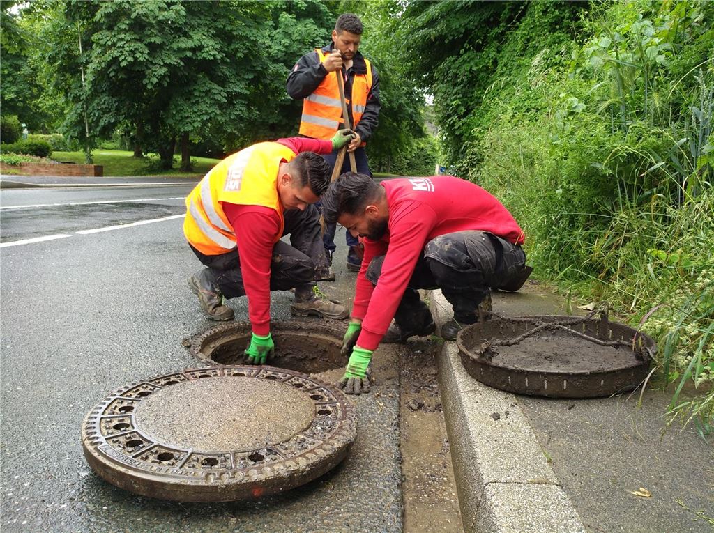 Stadt prüft fehlerhafte Kanalanschlüsse: Für Hausbesitzer kann das teuer werden Drei Bauarbeiter kontrollieren und reinigen einen Regenwasserkanal.