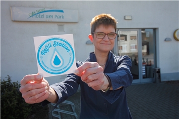 Das Neue Hotel am Park in Fröndenberg bietet einen speziellen Service für Radfahrer, die auf dem Ruhrtalradweg unterwegs sind: Sie können kostenlos ihre Trinkfalschen auffüllen lassen. Chefin Barbara Boeckler zeigt den Aufkleber, der ihr Hotel als „Refill-Station“ ausweist.