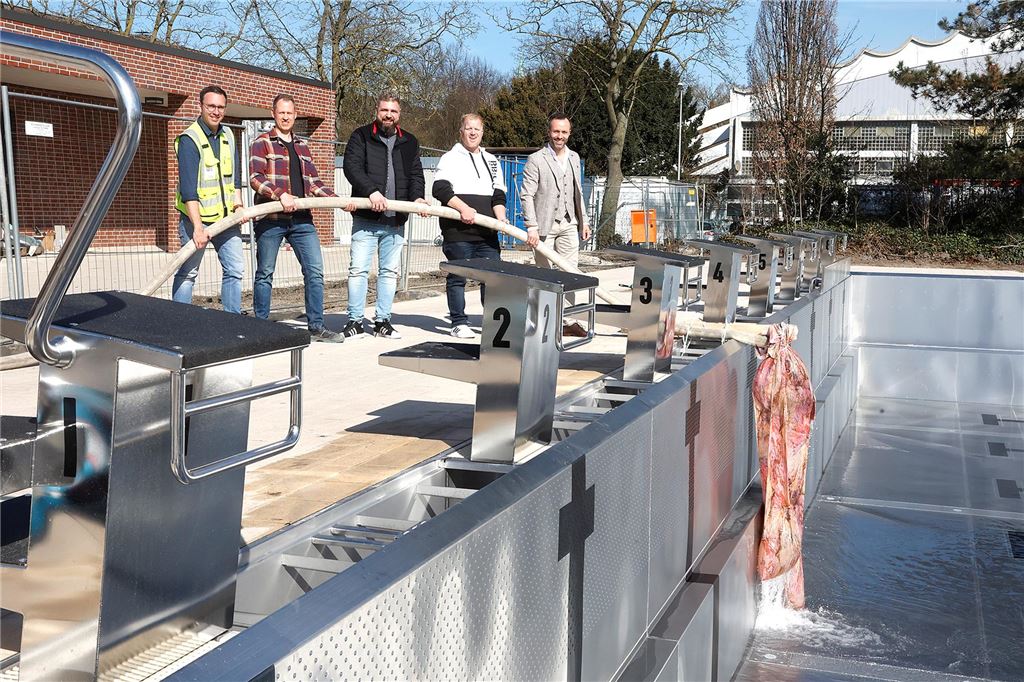 Kamener Hallenbad schließt: Einen Monat lang kein Schwimmbad Mehrere Mitarbeiter der GSW stehen an einem Schwimmbecken im neuen Sesekebad in Kamen und halten einen großen Wasserschlauch.