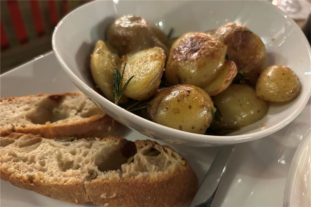 Perfektes Steak und ein Veggie-Experiment im Steakhouse „Le Bon Filet“ Eine weiße Schüssel mit Rosmarinkartoffeln, daneben liegen zwei Scheiben Brot im „Le Bon Filet Steakhouse“ in Dortmund