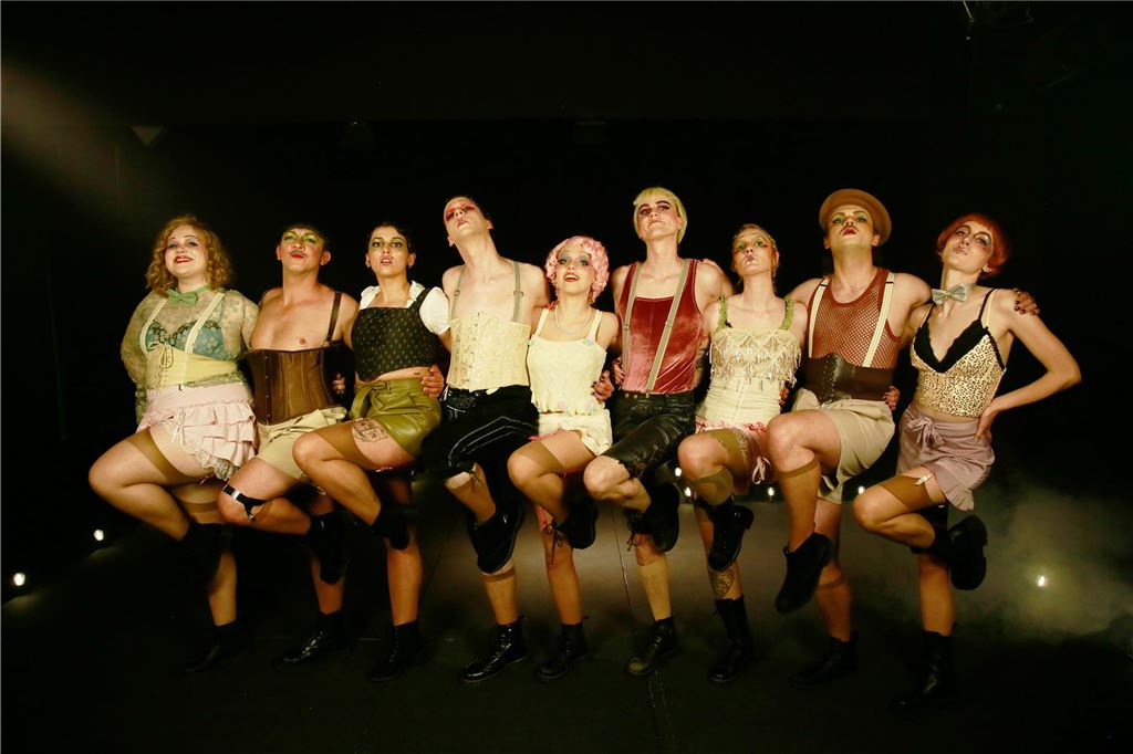 Theater Narrenschiff verwandelt sich in den „Garten Eden“ Auf dem Foto tanzt das Theaterensemble in Kostümen der 1920er- und 1930er-Jahre vor einem dunklen Hintergrund.