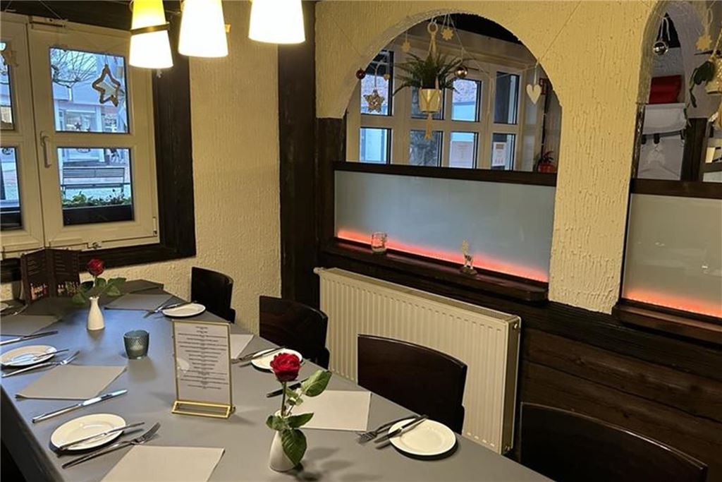 Buffet und Brunch zu Ostern: Diese Restaurants haben besondere Menüs Ein gedeckter Tisch im Restaurant Primo Amore ist zu sehen. Auf dem Tisch stehen Teller, Besteck, Servietten, Gläser, eine Menükarte und Vasen mit Rosen.