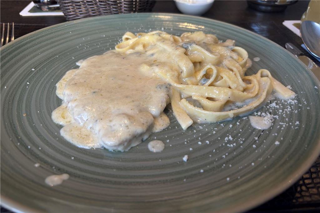 Mittagstisch im L’incontro: Wir testen das Angebot für unter 15 Euro Ein Schnitzel mit Soße und Nudeln liegt auf einem Teller.