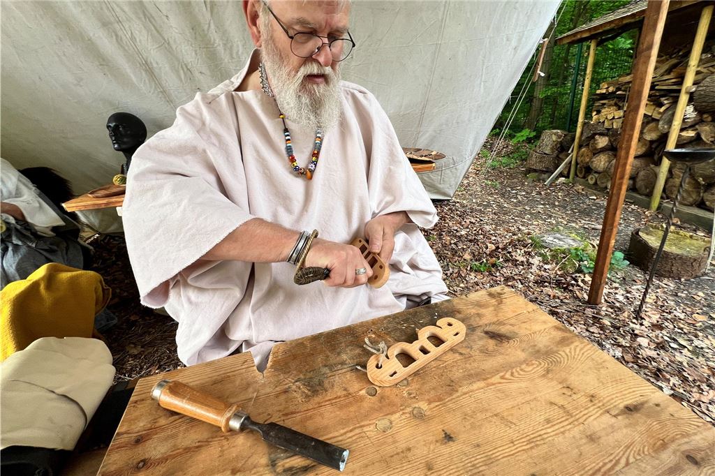 Ein Handwerker schnitzt etwas aus Holz.