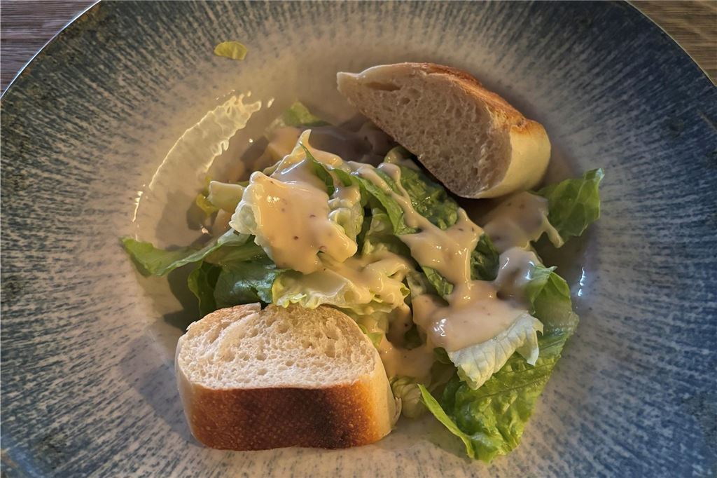 Steakrestaurant Wamo: Kann das All-you-can-Steak-Konzept überzeugen? Ein grüner Salat mit Honig-Senf-Soße und Baguettescheiben im Wamo in Dortmund.