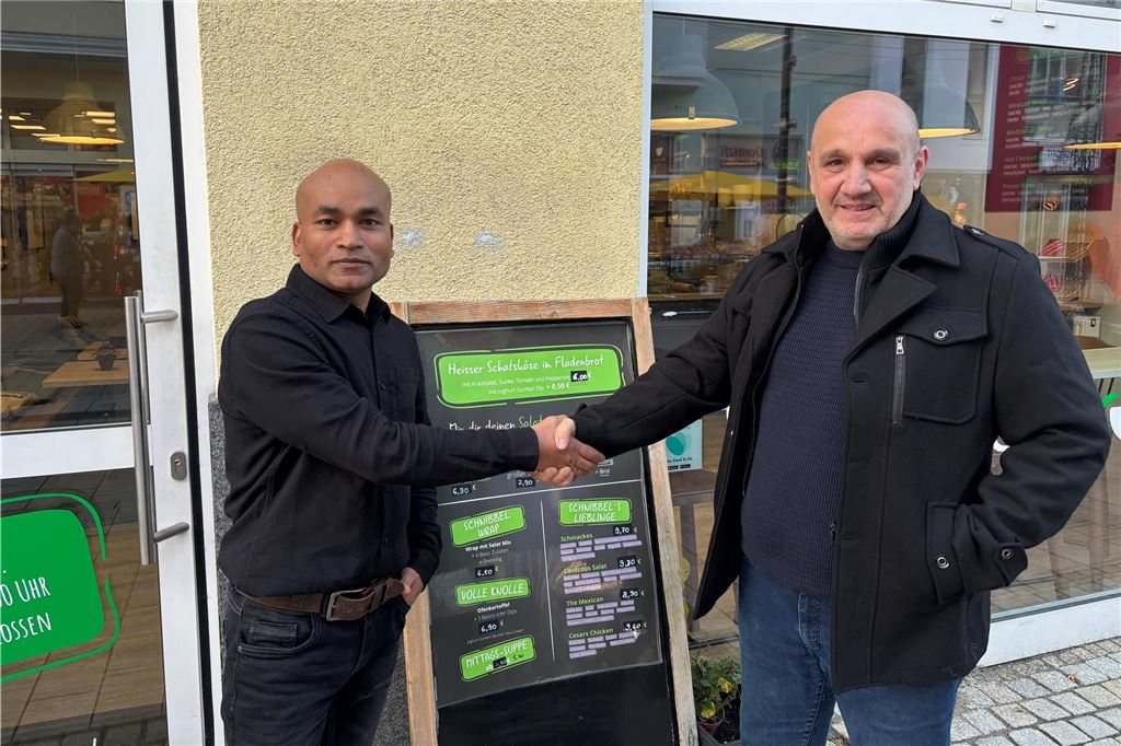 Neuer Inhaber gefunden: Zukunft von Schnibbelgrün gesichert Der neue Inhaber von Schnibbelgrün Hossain Howlader (l.) steht gemeinsam mit dem ehemaligen Inhaber Mustafa Nergiz (r.) vor der Schnibbelgrün Salatbar. Die beiden geben sich die Hand.