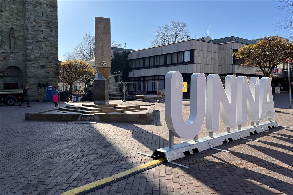 Baustelle, Festa, dann Sandkasten: Unna auch 2025 sommerlich möbliert Vor dem Rathaus und der Katharinenkirche in Unna steht ein großer, weißer 3D-Schriftzug: "UNNA". Dahinter ist eine Baustelle.
