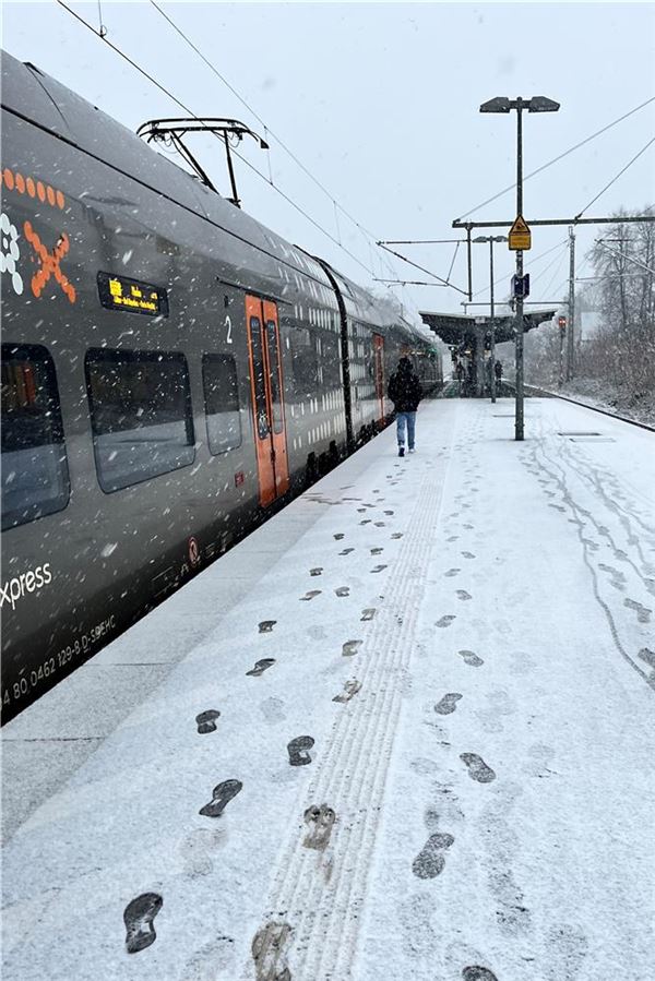 Schneebedeckter Bahnsteig mit Zug am Bahnhof Kamen.