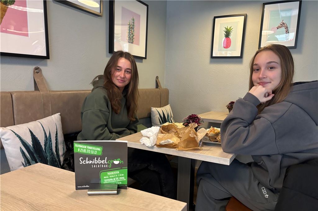 Neuer Inhaber gefunden: Zukunft von Schnibbelgrün gesichert Die beiden Schnibbelgrün-Kundinnen Maja (l.) und Emily (r.) sitzen an einem Tisch im Schnibbelgrün haben einen Wrap gegessen. Die beiden freuen sich auf Abwechslung in der Unnaer Gastronomie.