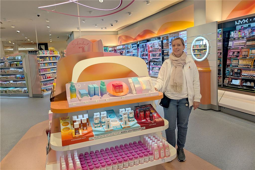 Nach Umbau eröffnet dm wieder: SB-Kassen und noch viel mehr Neues Eine Mitarbeiterin präsentiert die Regale mit Schönheitsprodukten in einem großen Drogeriemarkt.