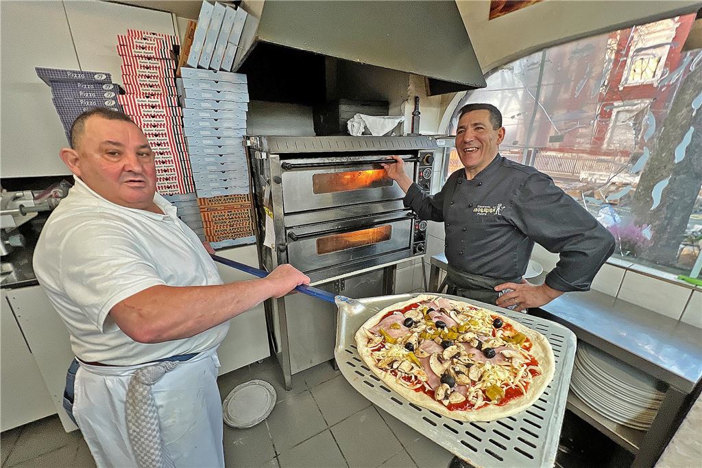 Pizzeria Taormina steht vor der Rückkehr: Es soll Änderungen geben Pizzeria Taormina an der Friedrich-Ebert-Straße in Unna: Salvatore Santoro (links) will einen belegten Pizza-Rohling in den Ofen schieben. Bruder Angelo Santoro öffnet die Ofenklappe.