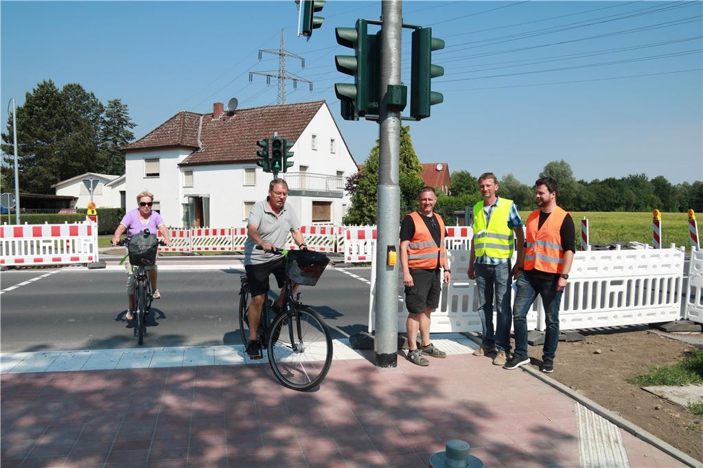 Die Ampel an der Hammer Straße ist mal komplett aus, mal grundlos rot Zwei Radfahrer queren die Ampel an der Hammer Straße in Unna. Neben der Fußgängerampel stehen drei Männer mit Warnwesten.