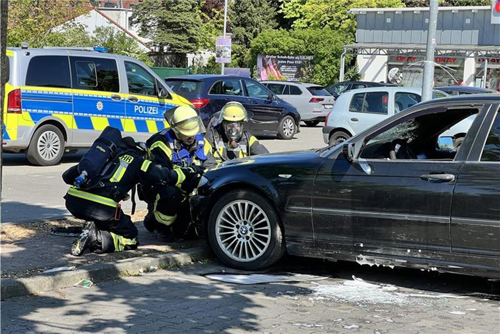 Auto hat in der Stadtmitte von Bergkamen gebrannt Feuerwehrleute beschäftigen sich mit der Motorhaube eines Fahrzeugs, dessen Innenraum gebrannt hat.