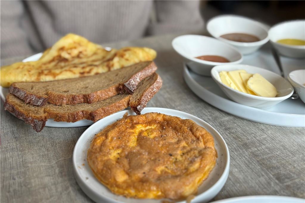 Restaurant-Check: Bei „Amlounge“ kann man den ganzen Tag frühstücken Auf dem Foto ist ein Frühstück mit Omelett, Brot, Butter und Dips zu sehen. Die Speisen sind auf kleinen, weißen Tellern angerichtet.