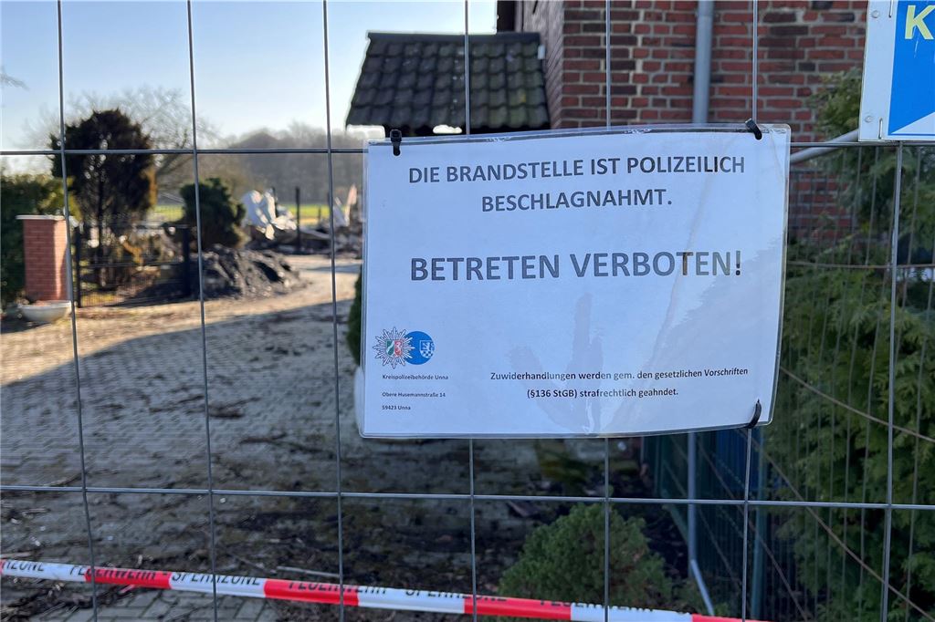 Verheerender Brand: Waffenverdacht führte Ermittler auf den Bauernhof Ein Schild mit der Aufschrift "Die Brandstelle ist polizeilich beschlagnahmt. Betreten verboten!" hängt an einem Bauzaun, der eine abgebrannte Hofstelle in Unna absperrt