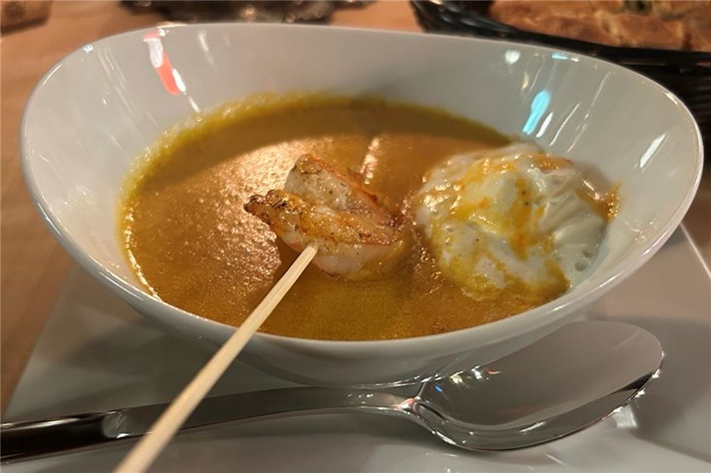 Perfektes Steak und ein Veggie-Experiment im Steakhouse „Le Bon Filet“ Eine weiße Suppenschüssel mit Suppe und einer Garnele auf einem Holzspieß im „Le Bon Filet Steakhouse“ in Dortmund.