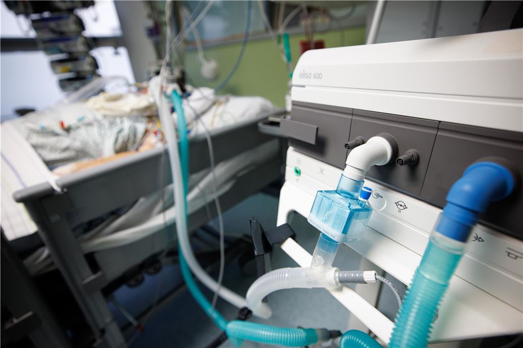 Staatsanwaltschaft ermittelt nach Tod einer Patientin (22) Auf diesem Symbolbild liegt ein Mensch in einem Intensiv-Bett. Im Vordergrund ist eine Herz-Lungen-Maschine zu sehen.