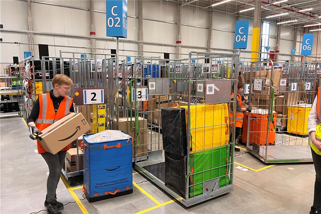 Amazon-Verteilzentrum: Spannende Einblicke und kritische Fragen Im Amazon-Verteilzentrum Unna trägt eine Mitarbeiterin ein Paket zu einem Transportwagen