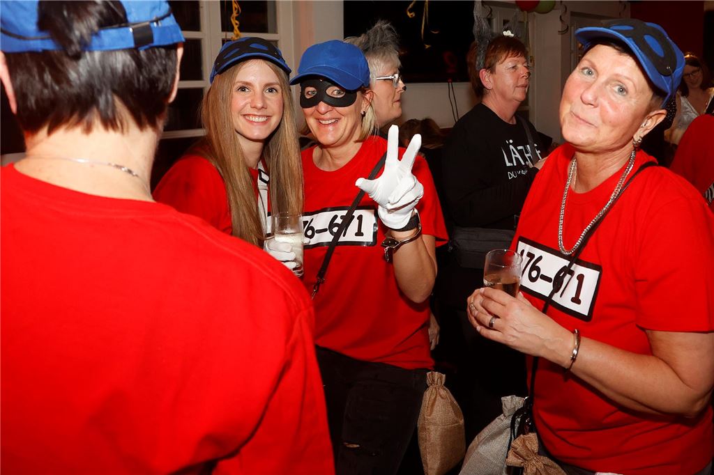 Eine Gruppe Frauen in roten Shirts mit blauer Kappe tanzen.