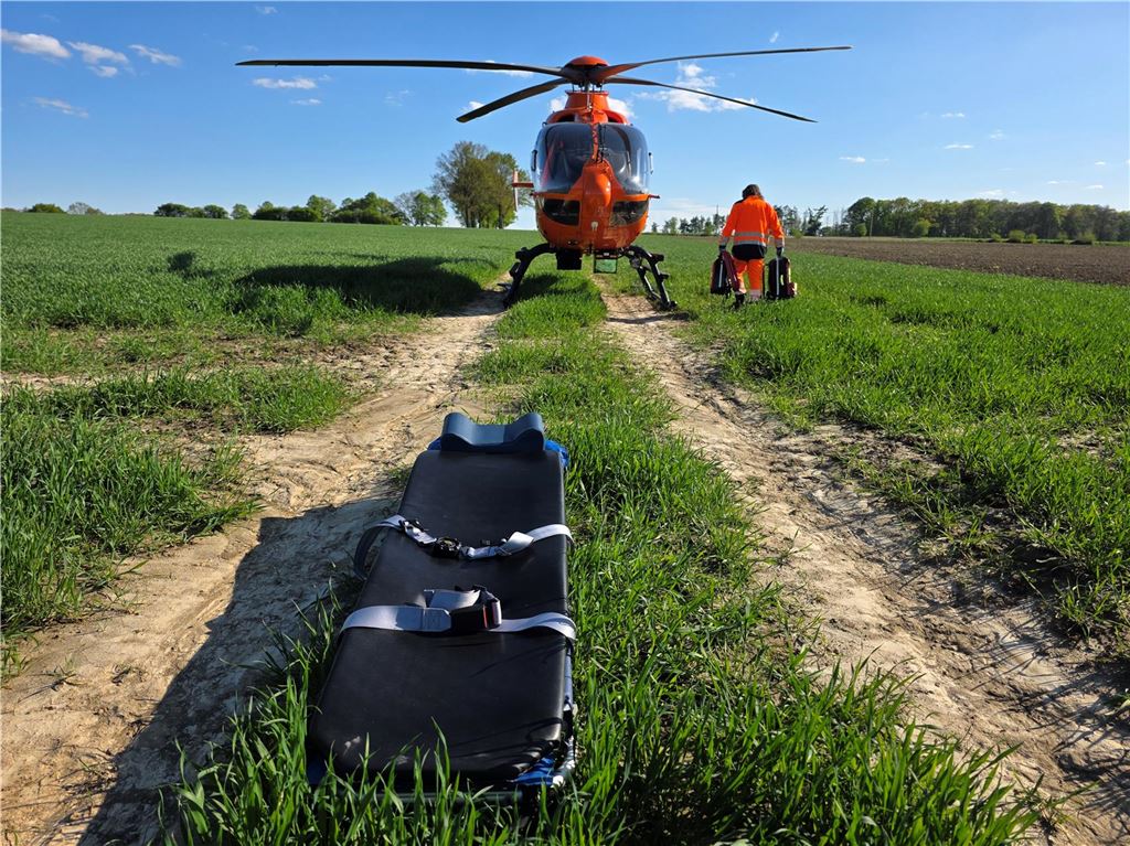 Reitunfall: Rettungshubschrauber landete auf Feld in Ostbüren Eine Trage liegt auf dem Raser. Christoph 9 befindet sich im Hintergrund.