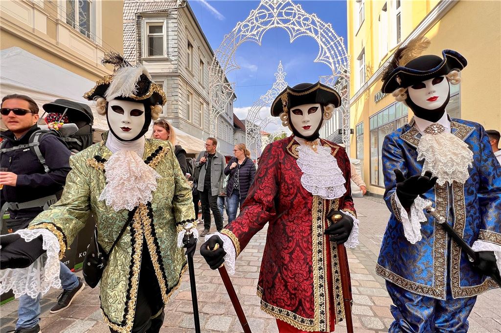 Drei kostümierte Menschen laufen vor der Eröffnung der Festa Italiana durch Unnas Straßen