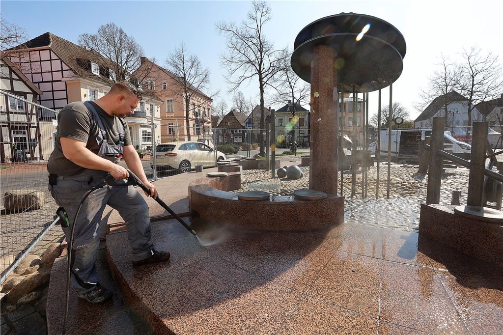 Benjamin Krause, Chef von Fliesen-Krause in Heeren, führt am Telgmann-Brunnen auf dem Alten Markt mit einem Mitarbeiter kleinere Reparaturen und Reinigungsarbeiten durch