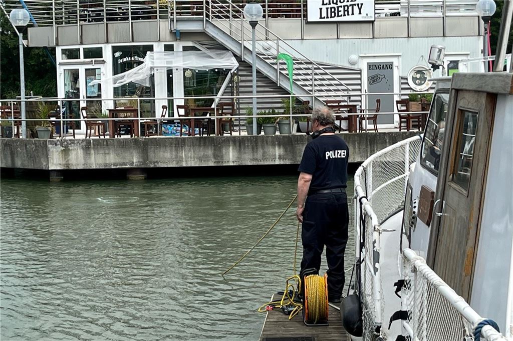 Babyleiche in der Marina befürchtet, toten Igel aus dem Wasser gezogen Ein Polizist steht mit einer Leine in der Hand auf einem Steg.