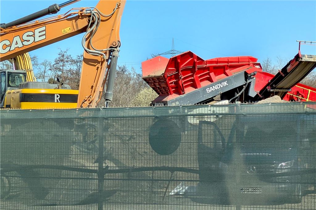 Evakuierung nach Bombenfund: Blindgänger wird kontrolliert gesprengt Ein Bulli steht neben Baggern und einem Stein-Schredder in einer Recyclingfirma.